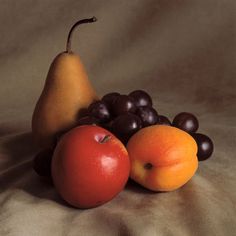 two pears, an orange and some blackberries on a tablecloth with a white background