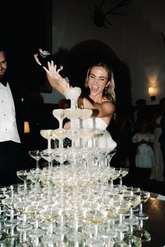 a man and woman standing next to a table full of wine glasses in front of them