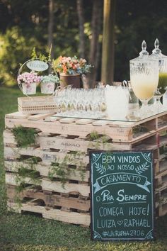 an outdoor bar made out of wooden pallets with chalkboard signs on the side