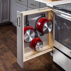 an open oven with pots and pans hanging from it's door in a kitchen