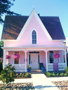 a pink house with flowers on the front porch