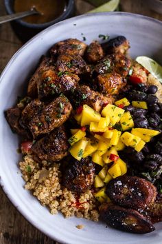 a white bowl filled with rice and meat next to a lemon wedge on top of a wooden table