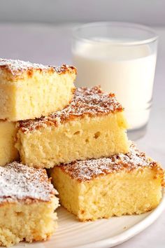 several pieces of cake on a plate next to a glass of milk