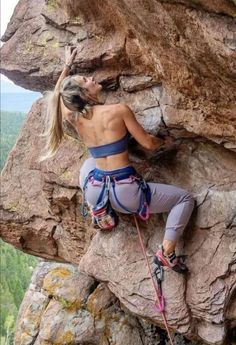 a woman climbing up the side of a mountain with her back to the camera and holding onto a rope