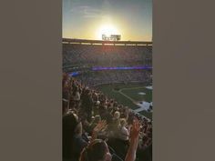 the sun is setting at a baseball game as people are in the bleachers