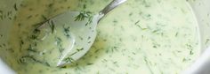 a white bowl filled with green liquid and a spoon