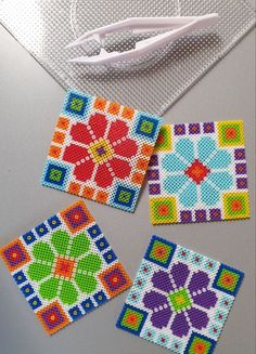 four different colored squares are sitting on a table next to some scissors and thread spools