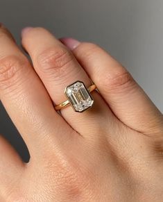 a woman's hand with a ring on it and an emerald stone in the middle