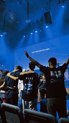 some people are standing in front of a blue screen and waving to the crowd with their hands up