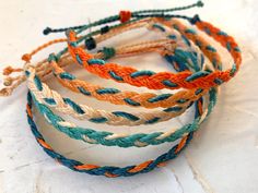 four different colored braided bracelets sitting on top of each other