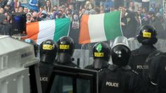 a group of police standing next to each other in front of a crowd with flags