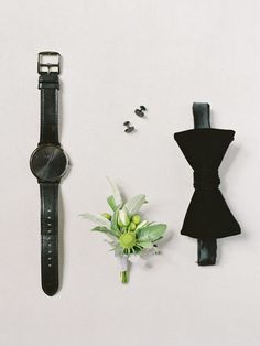 a flower and watch on a white surface next to it's strap, which is attached to a wall