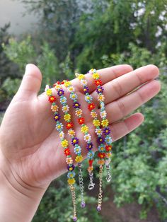 a person is holding some colorful beads in their hand and there are trees behind them