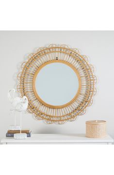 a round mirror sitting on top of a white shelf next to a vase and lamp