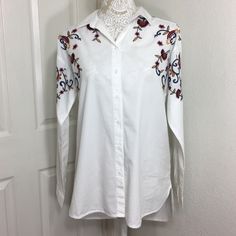 Cotton Button Up Shirt Featuring Embroidery Design Point Collar Long Sleeves Button Barrel Cuffs Split Hi-Lo Hem Back Yoke With Box Pleat Underarm To Underarm 21 Inches Front, Shoulder To Hemline 28 Inches Back, Shoulder To Hemline 30 Inches 100% Cotton Machine Wash White Button-up Top With Floral Embroidery, White Collared Embroidered Shirt, White Embroidered Collared Shirt, White Floral Embroidered Button-up Top, Embroidered Button-up Blouse For Fall, Fall Embroidered Button-up Blouse, White Embroidered Long Sleeve Shirt, Fall Floral Embroidered Button-up Blouse, Fall Floral Embroidery Button-up Blouse