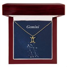 the zodiac sign is displayed in a wooden box with a gold chain and pendant on it