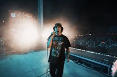 a man standing on top of a stage holding a microphone in front of a crowd