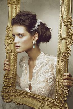 a woman is looking into a mirror with her hair in a bun and earrings on