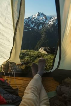 the view from inside a tent looking at mountains and snow capped peaks in the distance