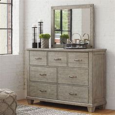 a dresser with a mirror and vases on top of it in front of a brick wall