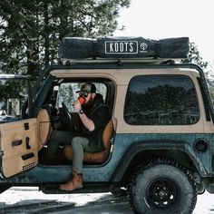 a man sitting in the driver's seat of a jeep drinking from a cup