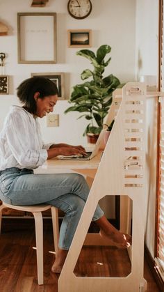 A woman sits working at her wooden home office desk. Small Sit Stand Desk, Small Wfh Space, Diy Adjustable Desk, Aesthetic Standing Desk, Desk Alternatives, Makeshift Desk, Standing Desk Home Office