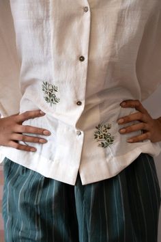 A boxy short sleeved shirt in khadi silk, with hand embroidered floral motifs and metal buttons. Crafted from luxurious khadi silk, this boxy short sleeved shirt boasts intricate hand-embroidered floral motifs and polished metal buttons to elevate your style game. Traditional Embroidered Linen Shirt, Traditional Linen Tops With Chikankari Embroidery, Traditional Floral Embroidered Festive Shirt, Traditional Floral Embroidery Festive Shirt, Traditional Linen Blouse With Floral Embroidery, Festive Short Sleeve Tops With Chikankari Embroidery, Short Sleeve Linen Blouse With Floral Embroidery, Cotton Short Sleeve Blouse With Resham Embroidery, Cotton Short Sleeve Top With Resham Embroidery