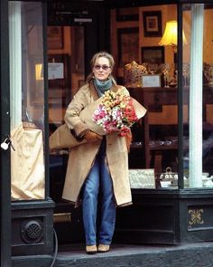 a woman walking out of a store holding flowers