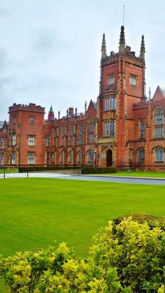 a large brick building sitting on top of a lush green field next to trees and bushes