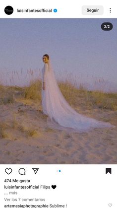 a woman in a white wedding dress standing on the beach with her veil pulled back