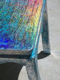 the back end of a wooden bench painted with multicolored holographics