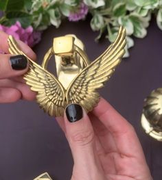 a person holding a gold ring with wings on it