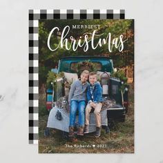 a christmas card with two kids sitting on the back of an old truck