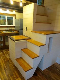 a kitchen with wooden stairs leading up to the upper floor and an island in the middle