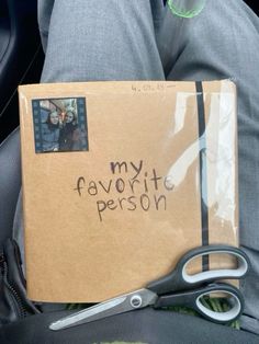 a box with some writing on it sitting in someone's lap next to a pair of scissors