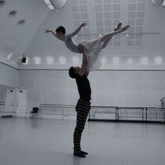 two people doing acrobatic tricks in an empty room