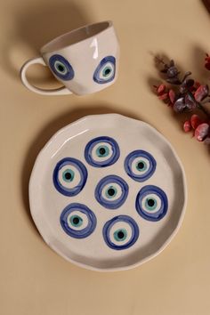 a white plate with blue eyes on it next to a cup