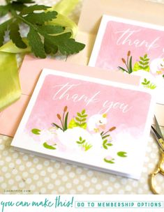 two thank you cards with flowers and greenery on them, sitting next to some scissors