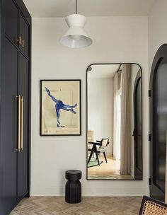 a room with a large mirror, black cabinet and wooden flooring in front of it