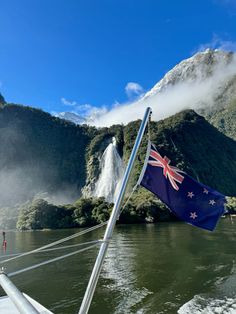 an australian flag is flying on the bow of a boat in front of a waterfall