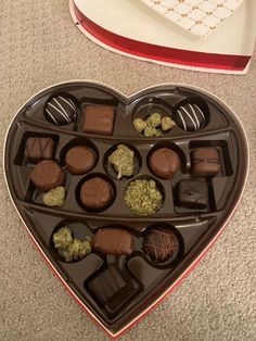 a heart shaped box filled with chocolates on top of a table next to a plate