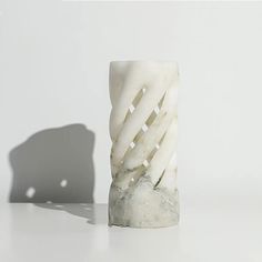 a white sculpture sitting on top of a table next to a shadow cast by a wall