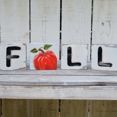 the word fall spelled out in block letters with a pumpkin painted on it's side