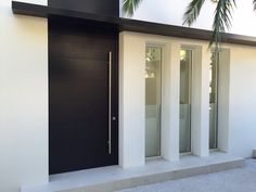 a black and white building with two doors on each side, and palm trees in the background