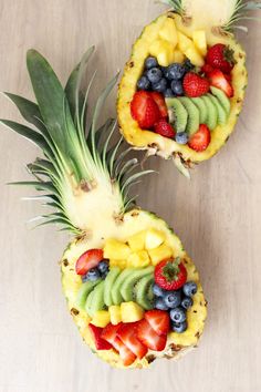 two pineapples with fruit arranged on them