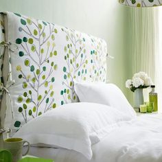 a bed with white linens and green wallpaper in a room that is well decorated