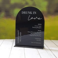 a black acrylic sign with the words drunk in love on it sitting on a wooden table