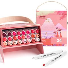 a pink box with markers and pens in it next to an artx set on a white background