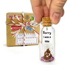 a hand holding a tiny glass bottle with a message in it next to a package