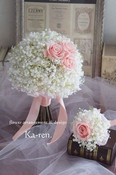 two pink and white flowers are in a vase on a table next to a book